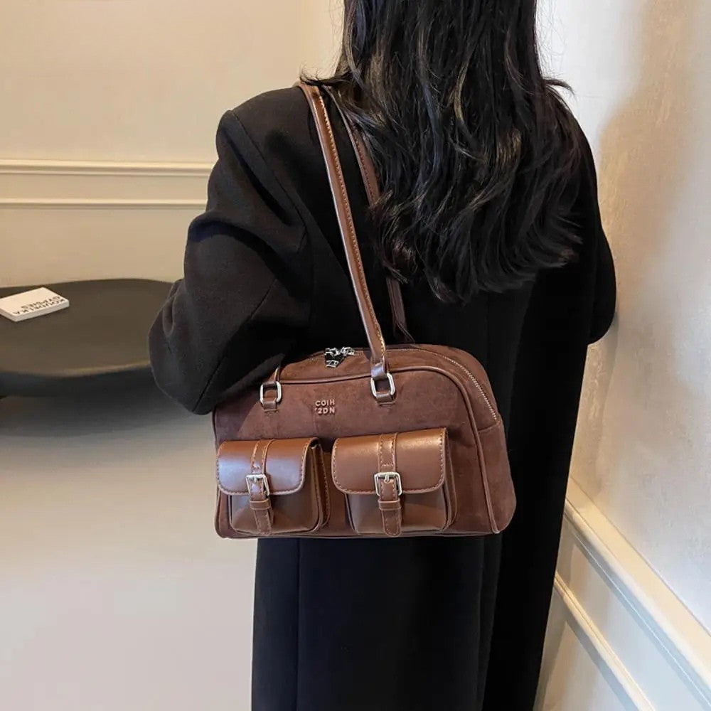 Bruine tas met gespen gedragen over zwarte outfit