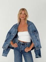 Model draagt Riley Oversized Denim Jacket in mid-wash denim met witte top en jeans
