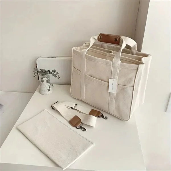 Beige canvas tote met stevige riemen en ruim hoofdvak.
