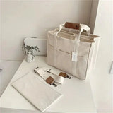 Beige canvas tote met stevige riemen en ruim hoofdvak.