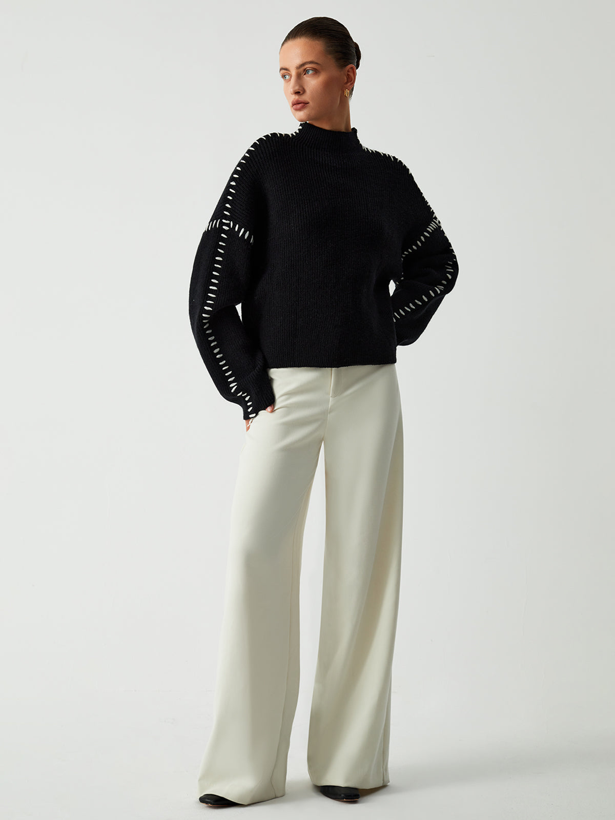 Zwarte trui oversized fit gedragen met witte broek
