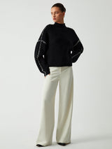 Zwarte trui oversized fit gedragen met witte broek
