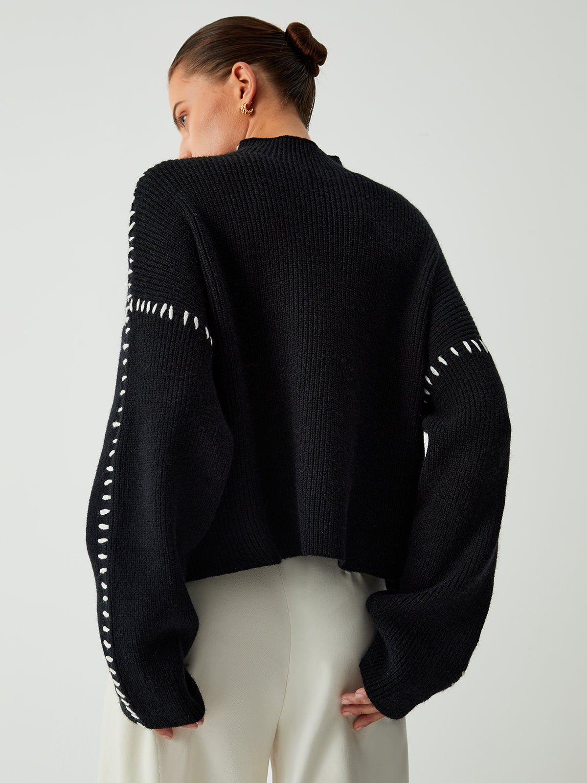 Zwarte gebreide sweater met mock neck van achteren

