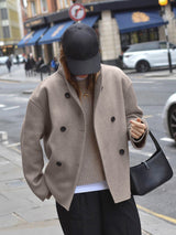 Model met tas in oversized jas in beige
