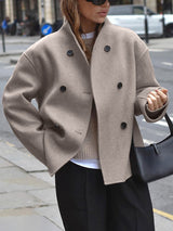 Model draagt oversized jas in beige op straat
