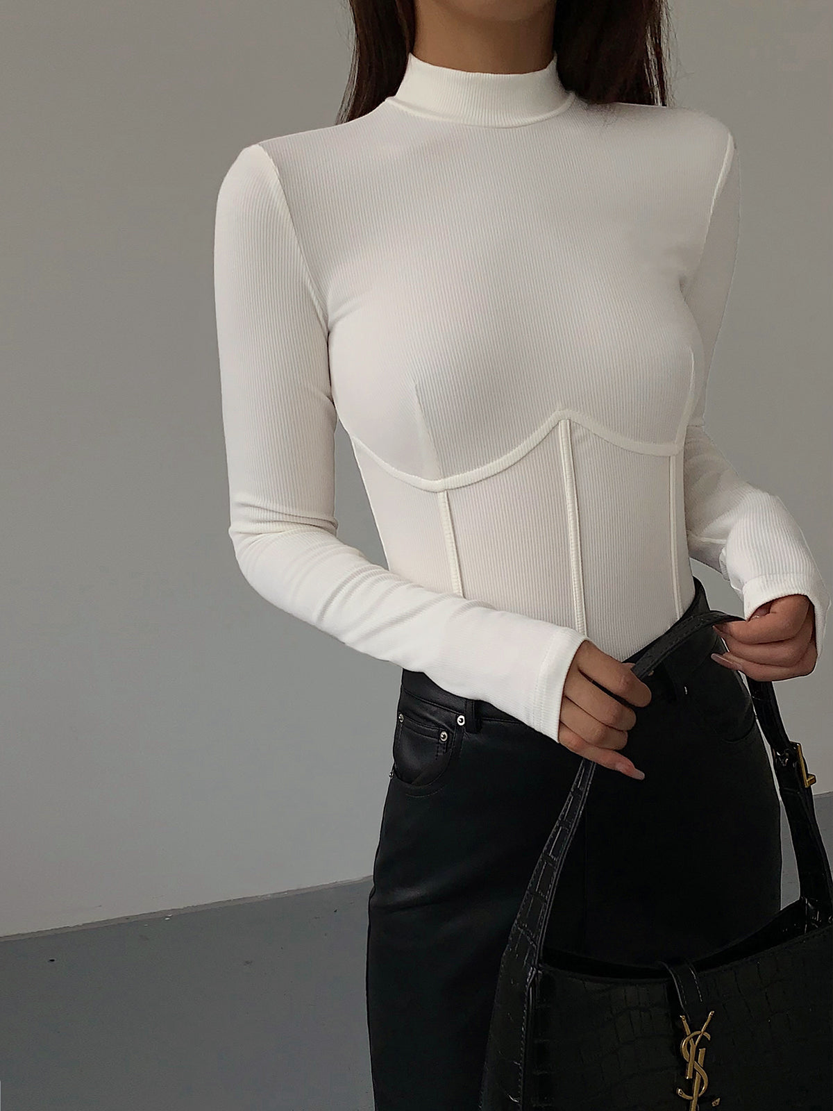 Model draagt witte Meliora top met piping en mock neck
