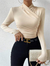 Model draagt beige cross-over top met lange mouwen
