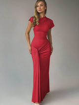Model in de rode Celina Lace-Up Gown, elegante pasvorm en subtiele glans
