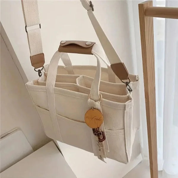 Beige canvas tote met stevige riemen en ruim hoofdvak.