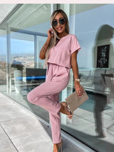 vrouw in blush roze jumpsuit op balkon
